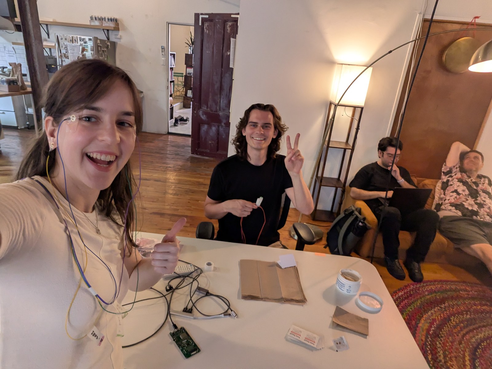 A smiling player wearing EOG electrodes gives a thumbs up beside a competitor flashing a peace sign at the tournament table.
